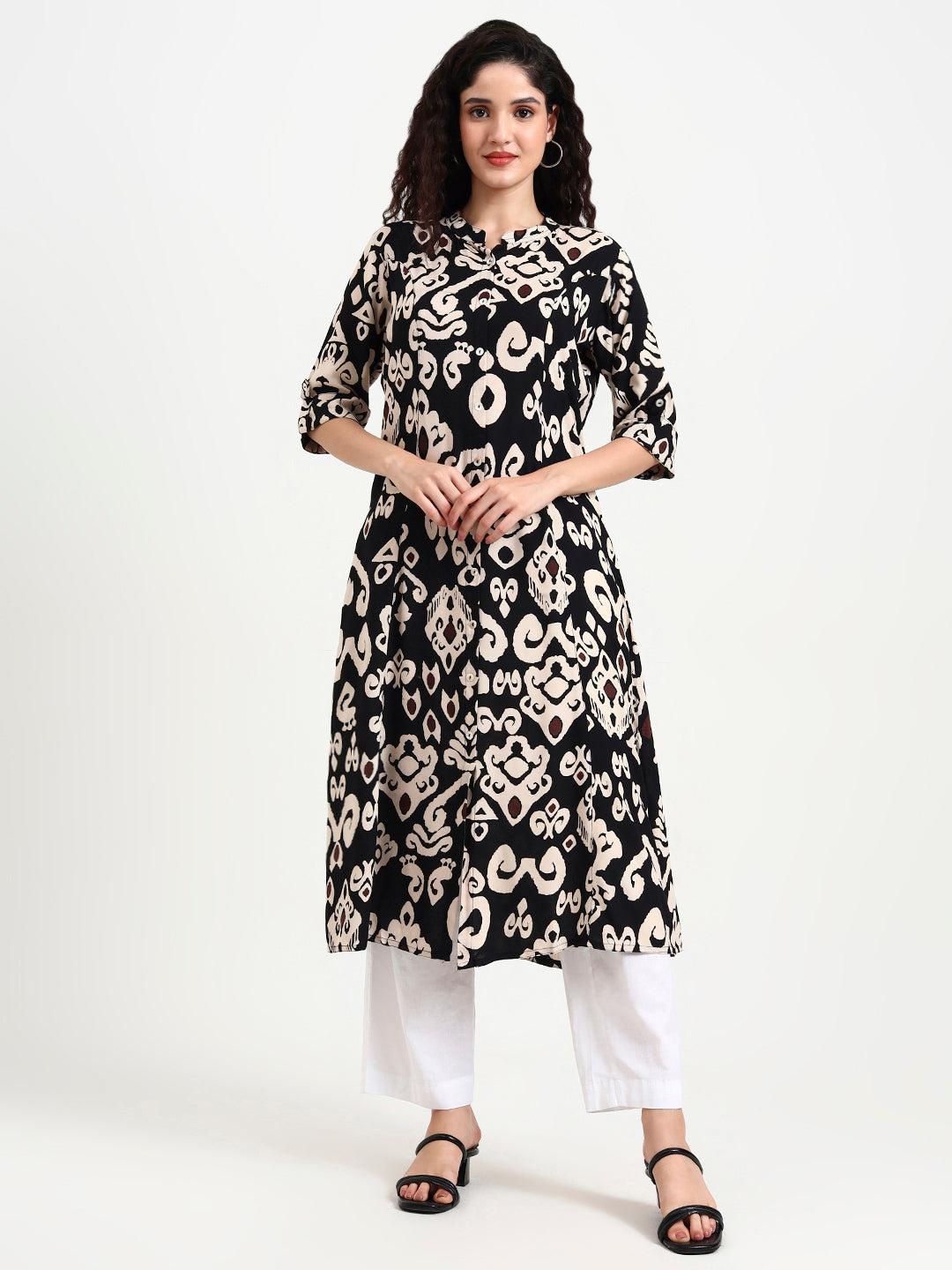 Woman wearing a black and white patterned kurta with white pants on a white background