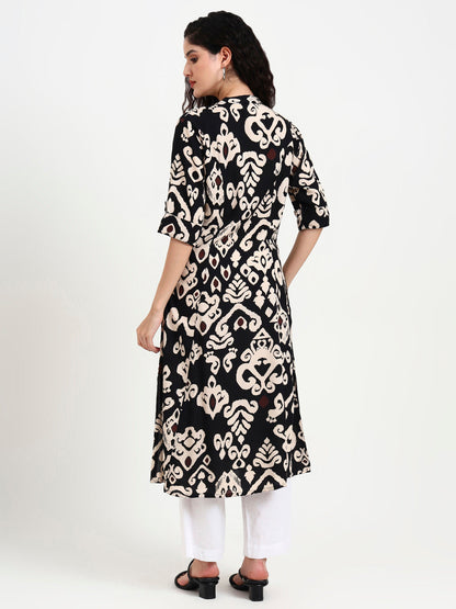 Woman wearing a black and white patterned kurta with white pants on a white background