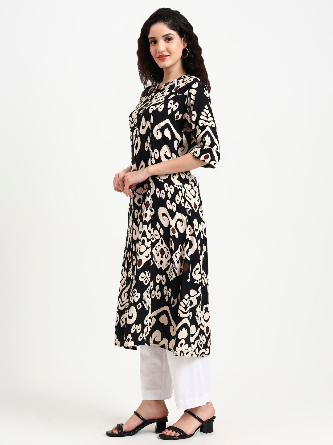 Woman wearing a black and white patterned kurta with white pants on a white background