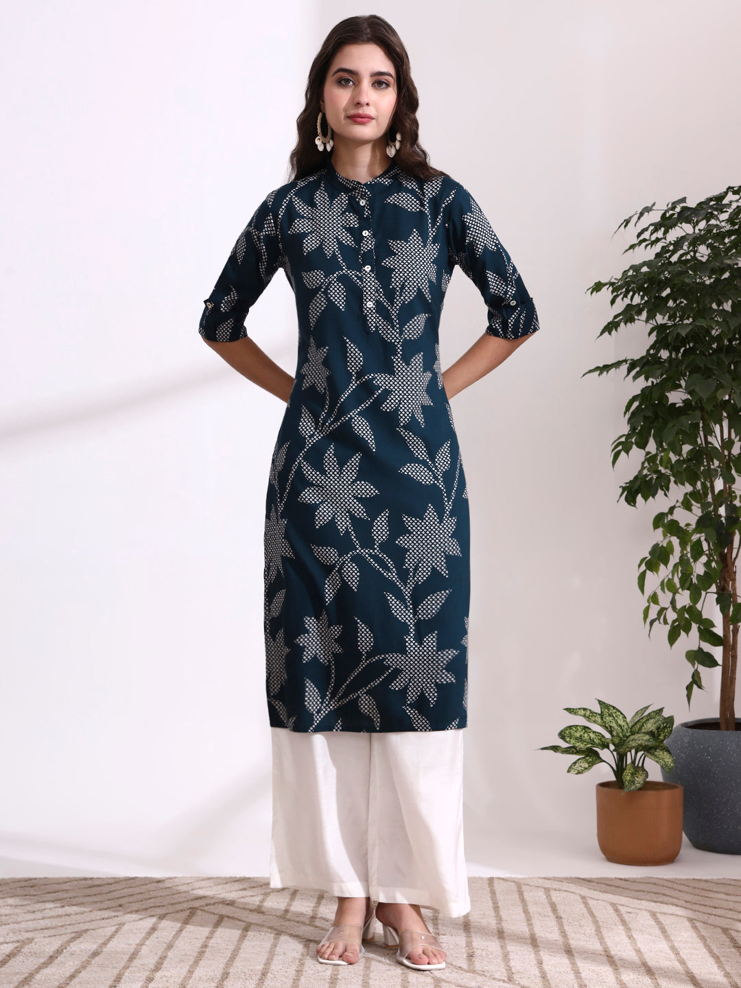 Woman wearing a dark blue floral patterned kurta with white pants in a minimalistic setting.