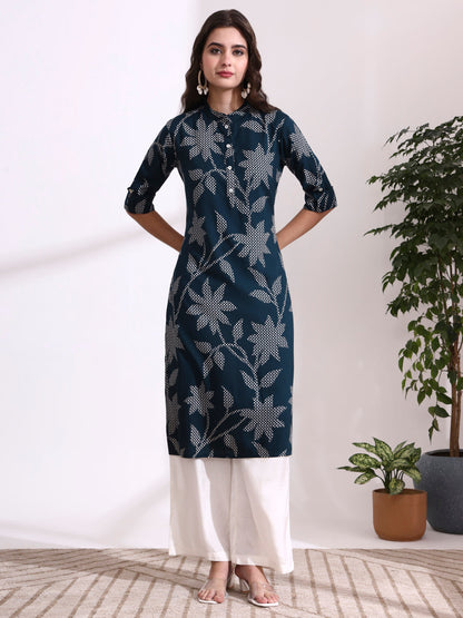 Woman wearing a dark blue floral patterned kurta with white pants in a minimalistic setting.