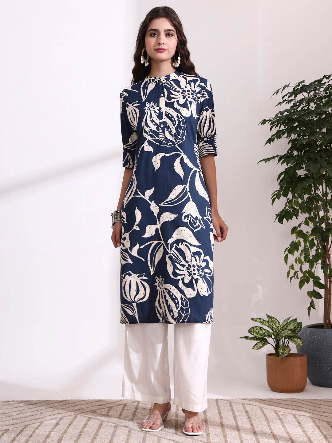 Woman wearing a navy blue floral patterned kurta with white pants in a minimalistic room.