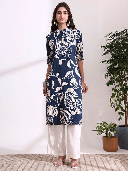 Woman wearing a navy blue floral patterned kurta with white pants in a minimalistic room.