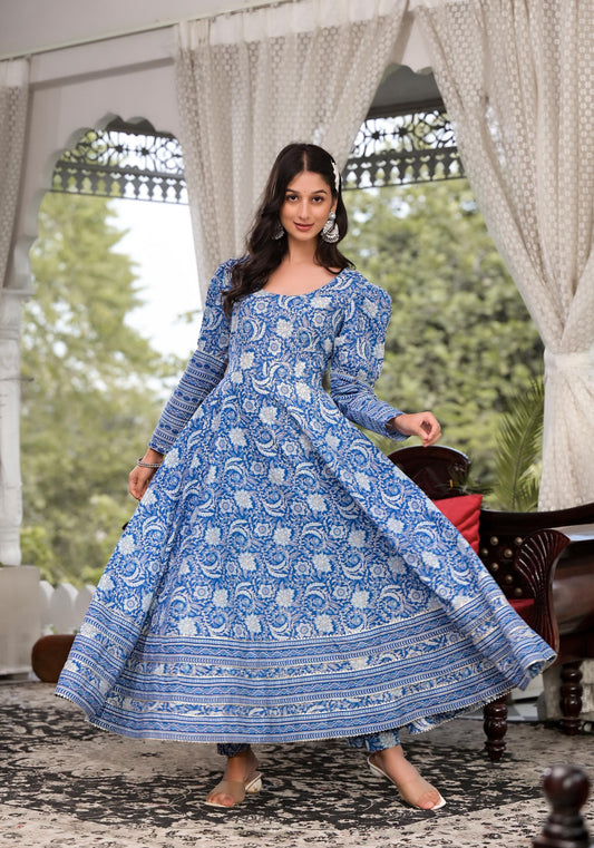 Woman wearing a blue floral dress standing in a decorated outdoor setting.