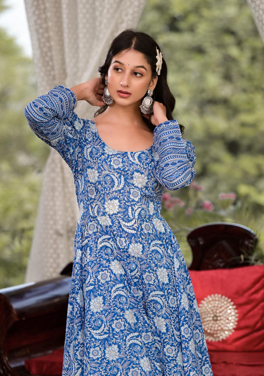 Woman wearing a blue patterned dress with a blurred outdoor background